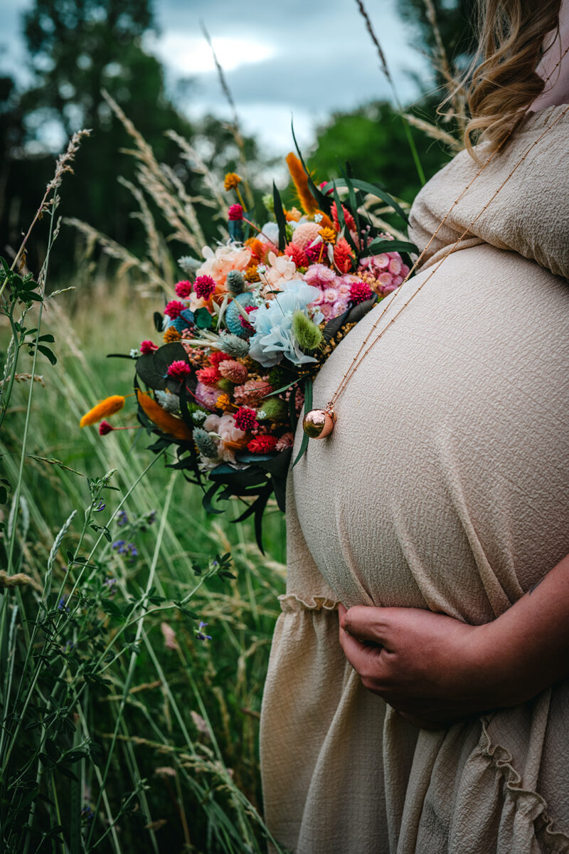 Shooting grossesse ventre avec bouquet de fleurs dans la prairie Sélestat