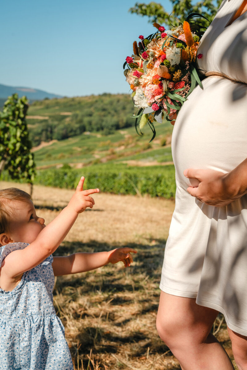 bébé qui veut toucher le ventre de sa maman et le bouquet de fleurs